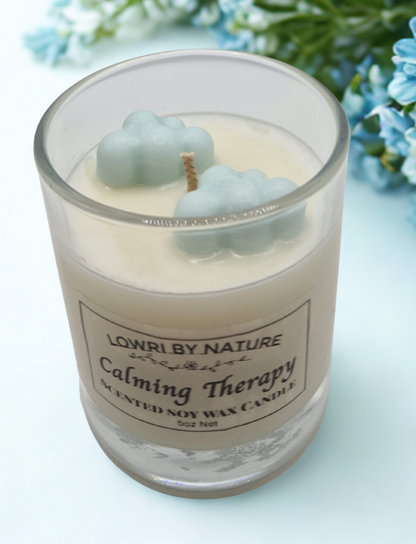 Candle labeled 'Calming Therapy' by Lowri by Nature with decorative elements on a light blue background.